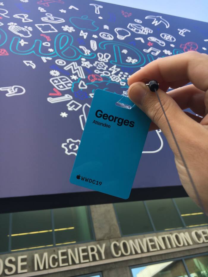 A
                                       photo of the WWDC19 blue badge with name
                                       George followed by the word Attendee and
                                       the logo of WWDC19. The background
                                       contains the graphics of the event
                                       printed on an canvas.  The canvas is on
                                       the front of the San Jose McEnery
                                       Convention Center. The words Ose McEnery
                                       Conevention Ce appear too.